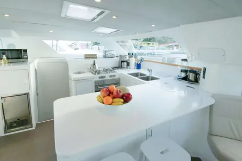 Galley with a gas stove, double sink, and a bowl of fruit on the counter