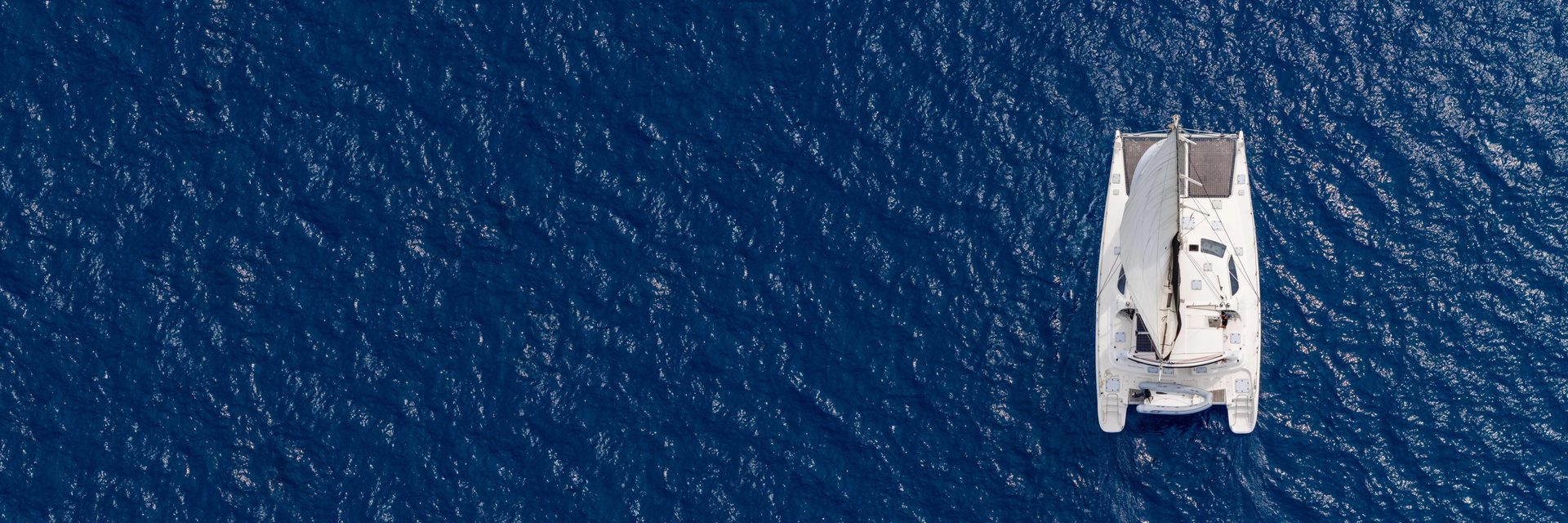S/V Moonstruck seen from directly overhead, sailing alone across deep blue open water